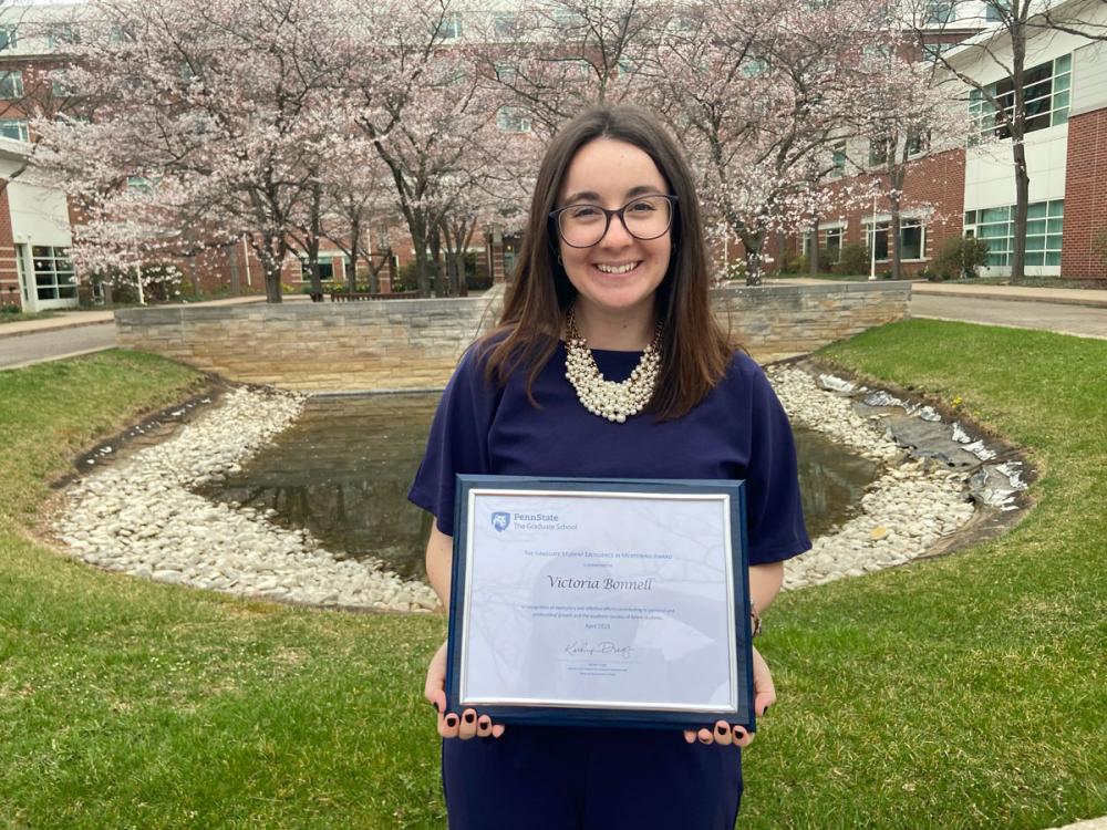 Bonnell stands outside holding plaque
