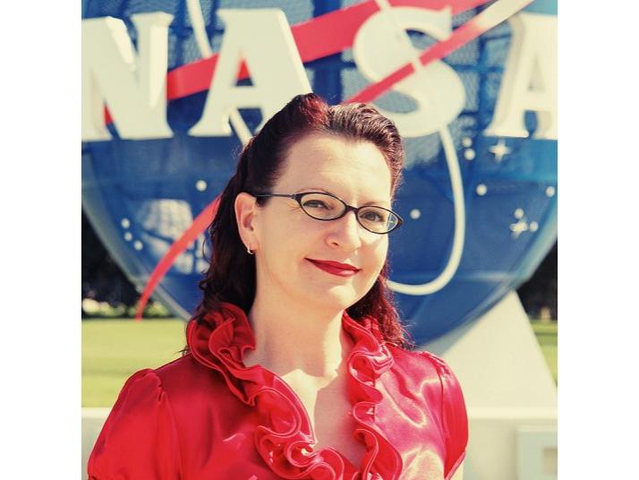 Elaine Seasly stands in front of a large NASA sign