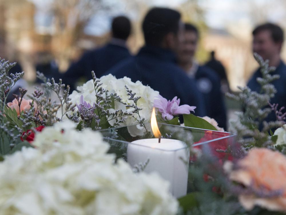 A lighted candle sits nestled among purple, white and pink flowers