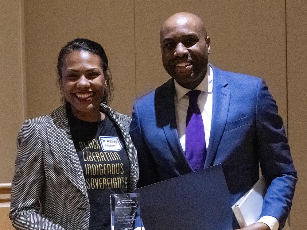 Woman on left holding award she was presented by man on right