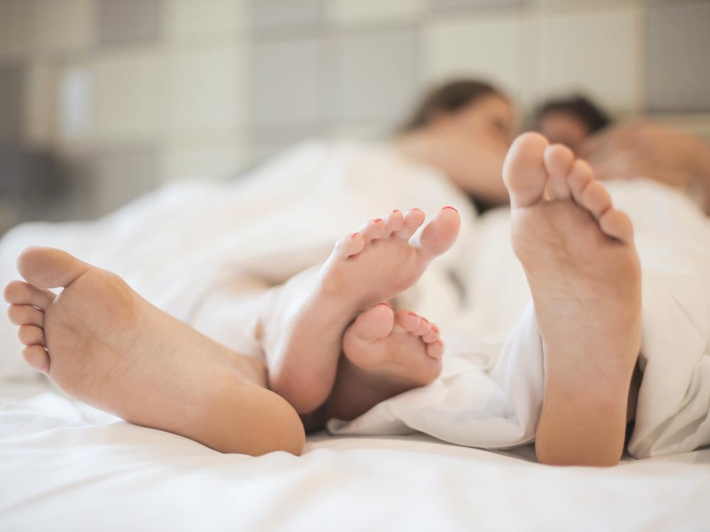 two people's feet in bed