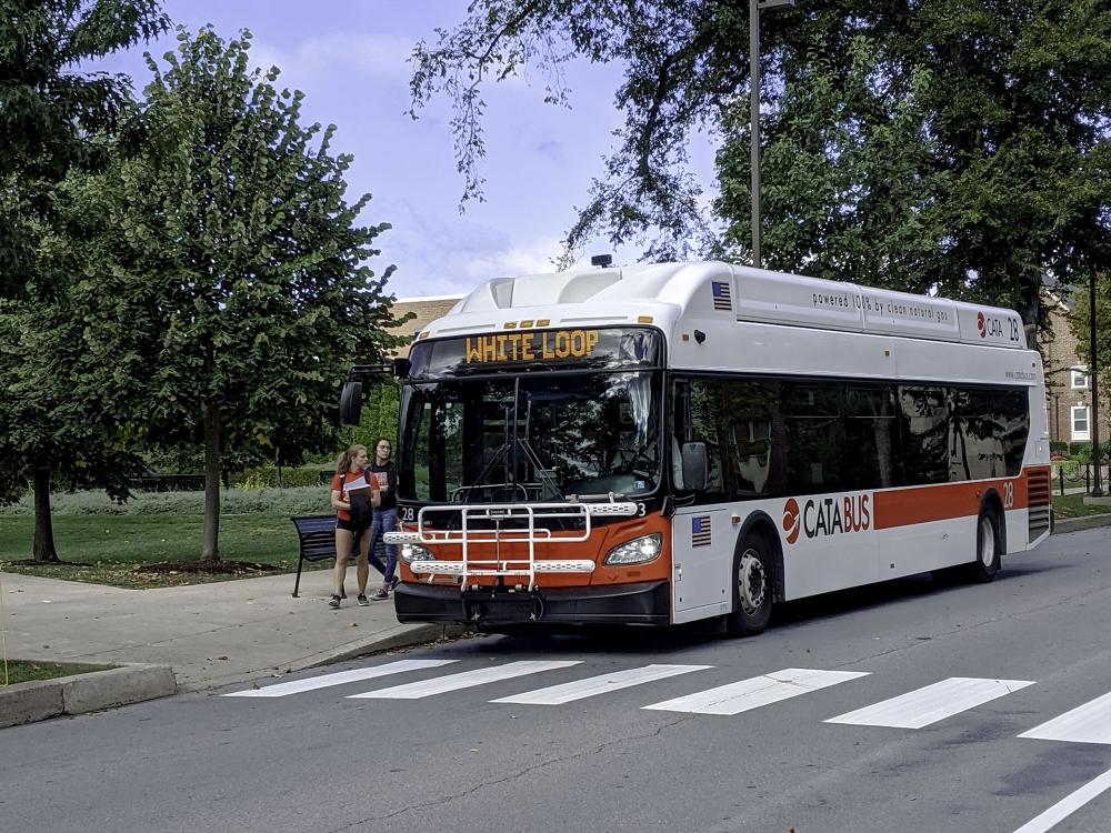 Students wait to climb aboard a White Loop CATA bus on Penn State's campus