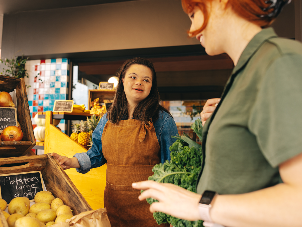 A young woman with Down syndrome assisting a customer in a grocery store. 
