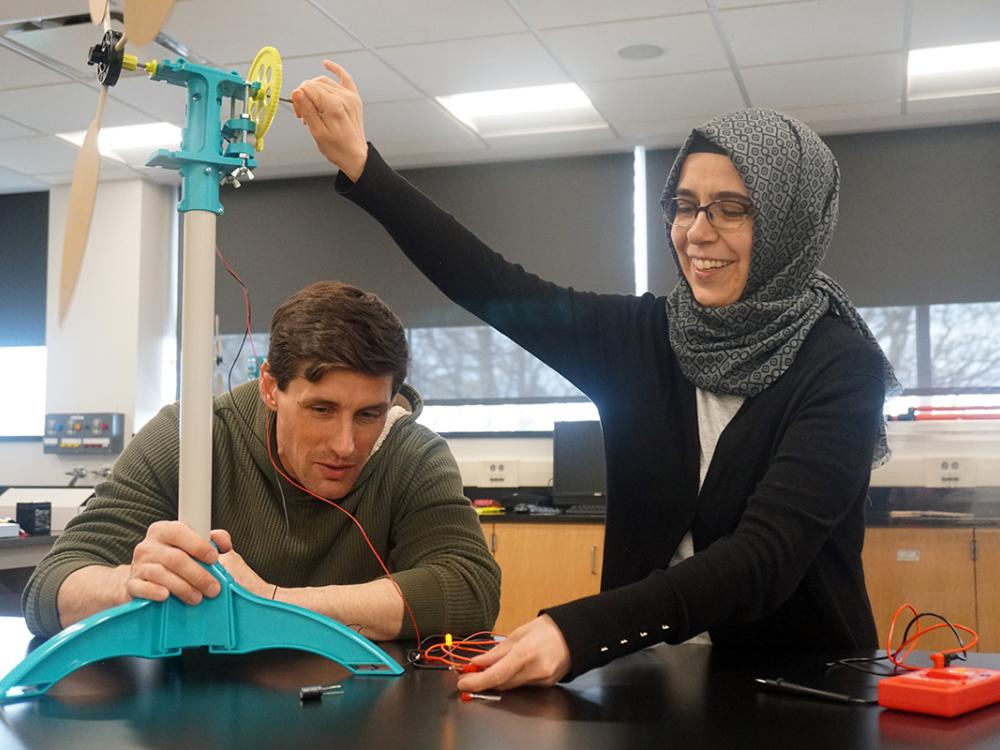 Instructor and student working with model wind turbine in a classroom.