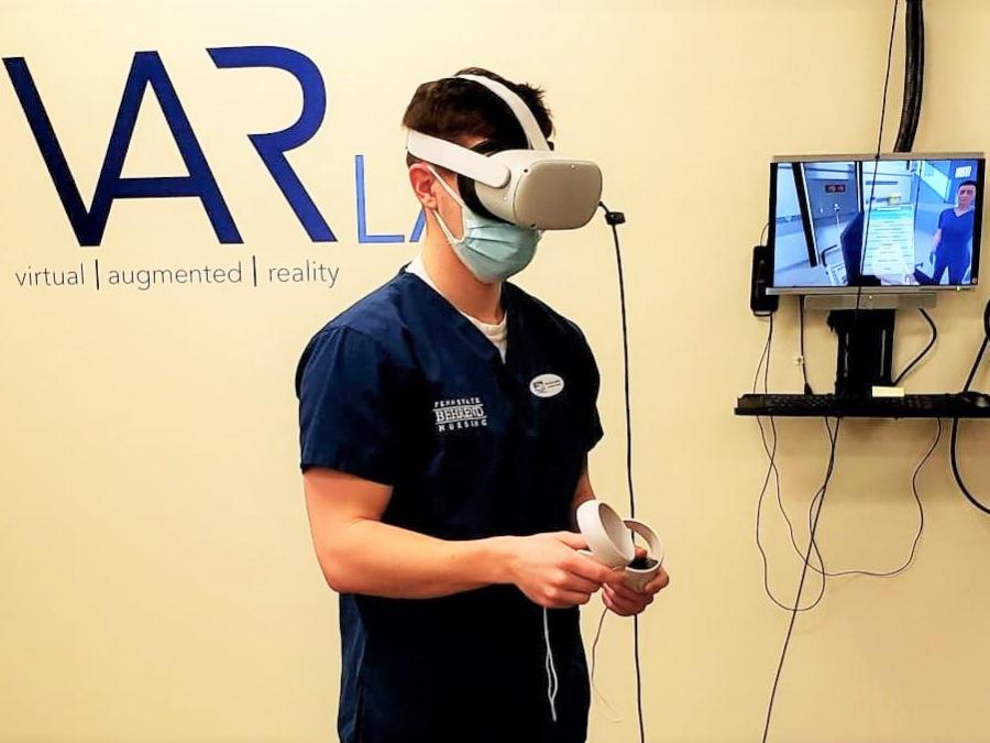 A male student in the nursing program at Penn State Behrend wears an Oculus headset while completing a VR simulation.