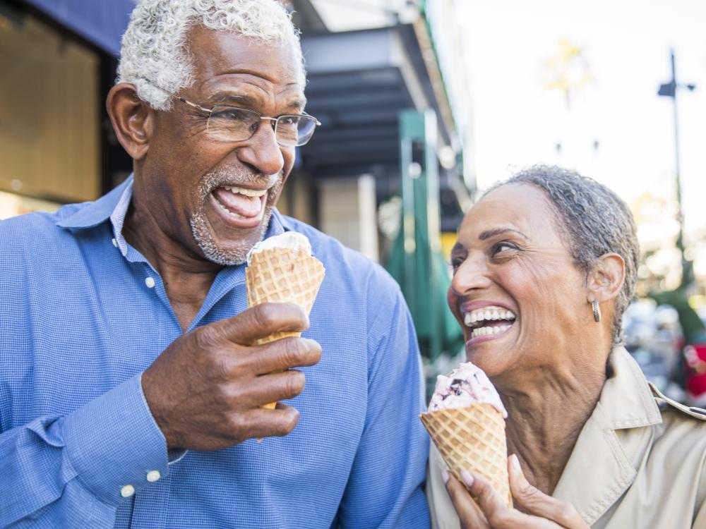 Older Black man and woman eating ice cream and smiling