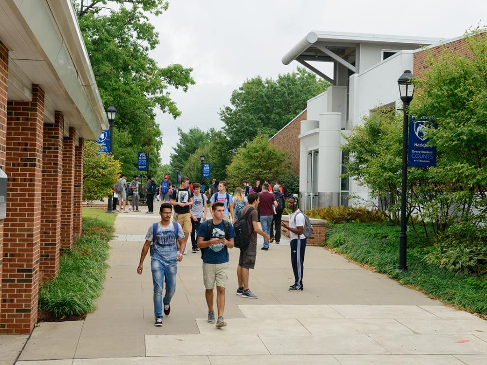 Students walking on a sidewalk at a college campus.