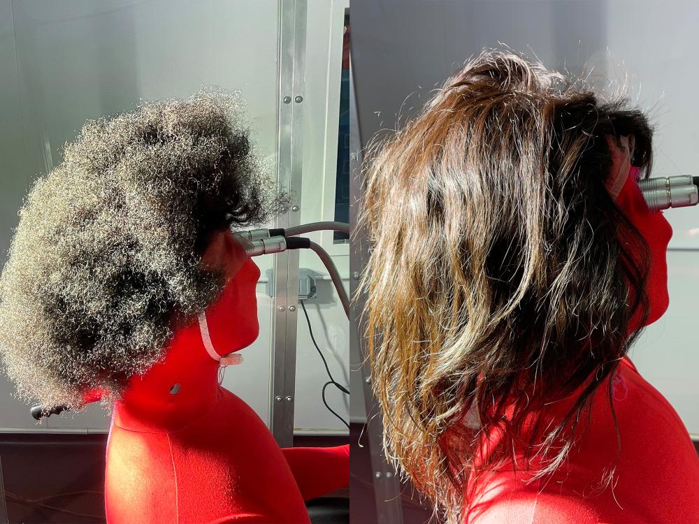 Side-by-side photos of a thermal manikin, connected to a power source, wearing tightly curled (left) and straight (right) human hair wigs.