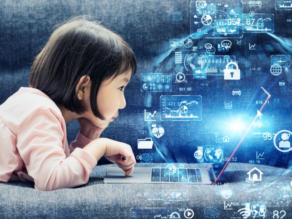 young girl with dark hair and pink shirt playing on laptop