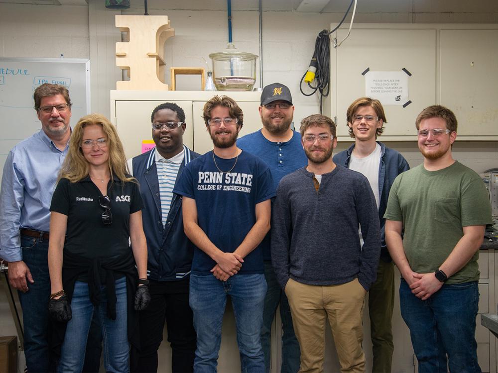 A group of students and two faculty pose in a laboratory for a group photo.