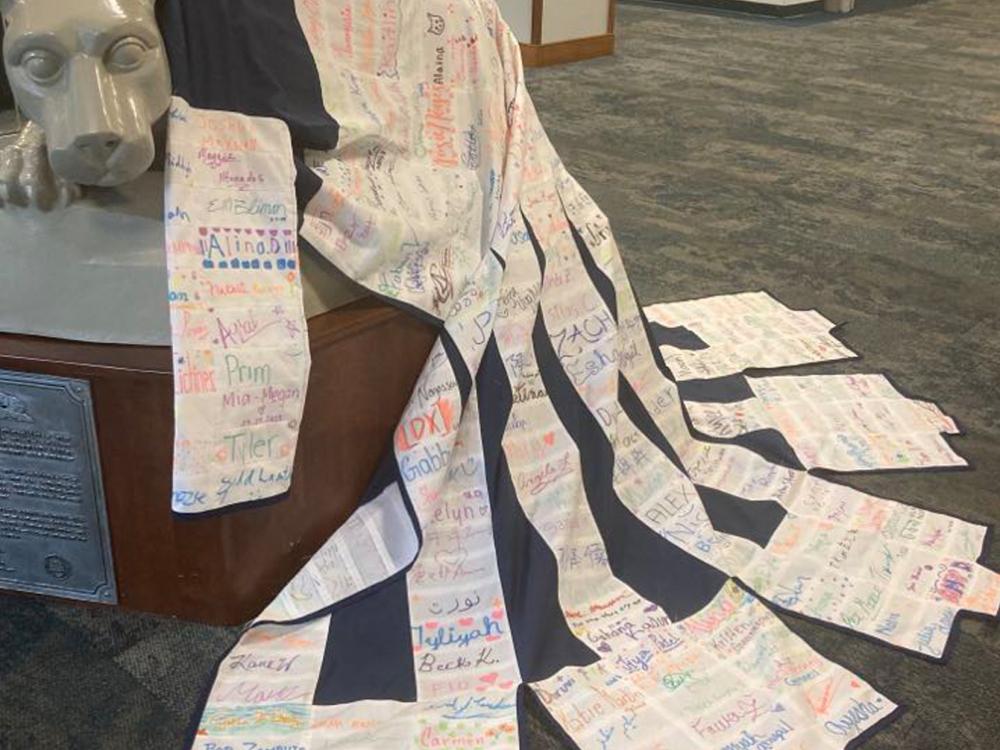 A photo of Emily Pettet's finished signature coat, displayed on the Nittany Lion statue inside Olmsted Building