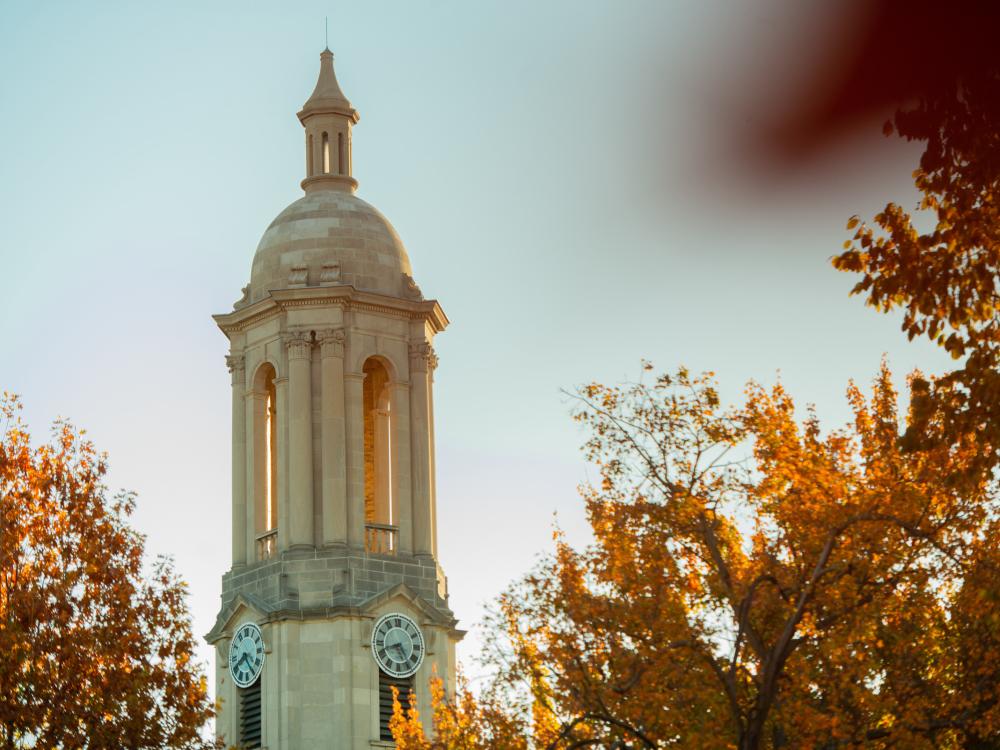 Old Main bell tower flanked by orange and yellow fall foliage