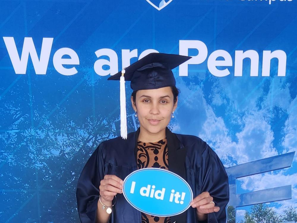 A woman stands in front of a Penn State-themed background.