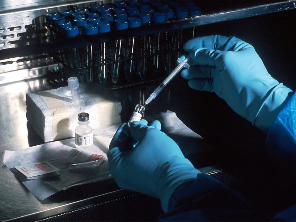 gloved hands holding syringe next to drug