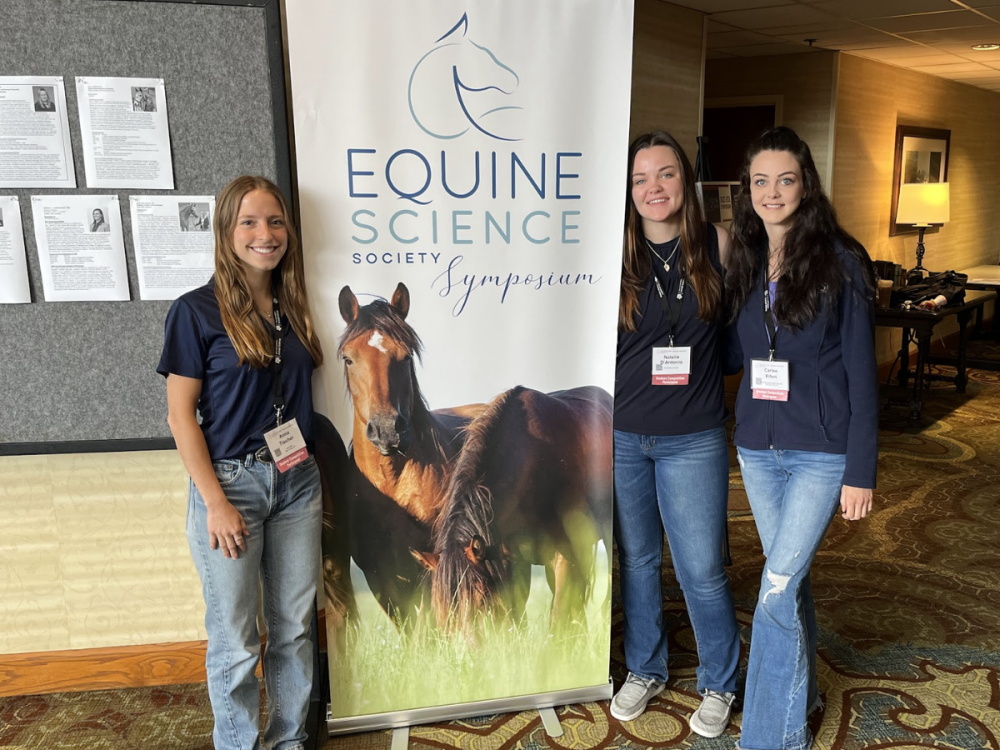 Three Penn State students pose at the symposium