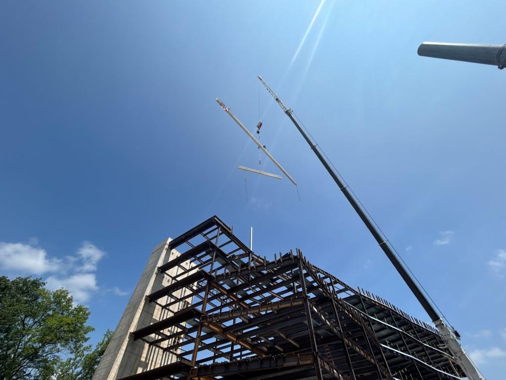 Photo of steel beam being raised by crane over building 