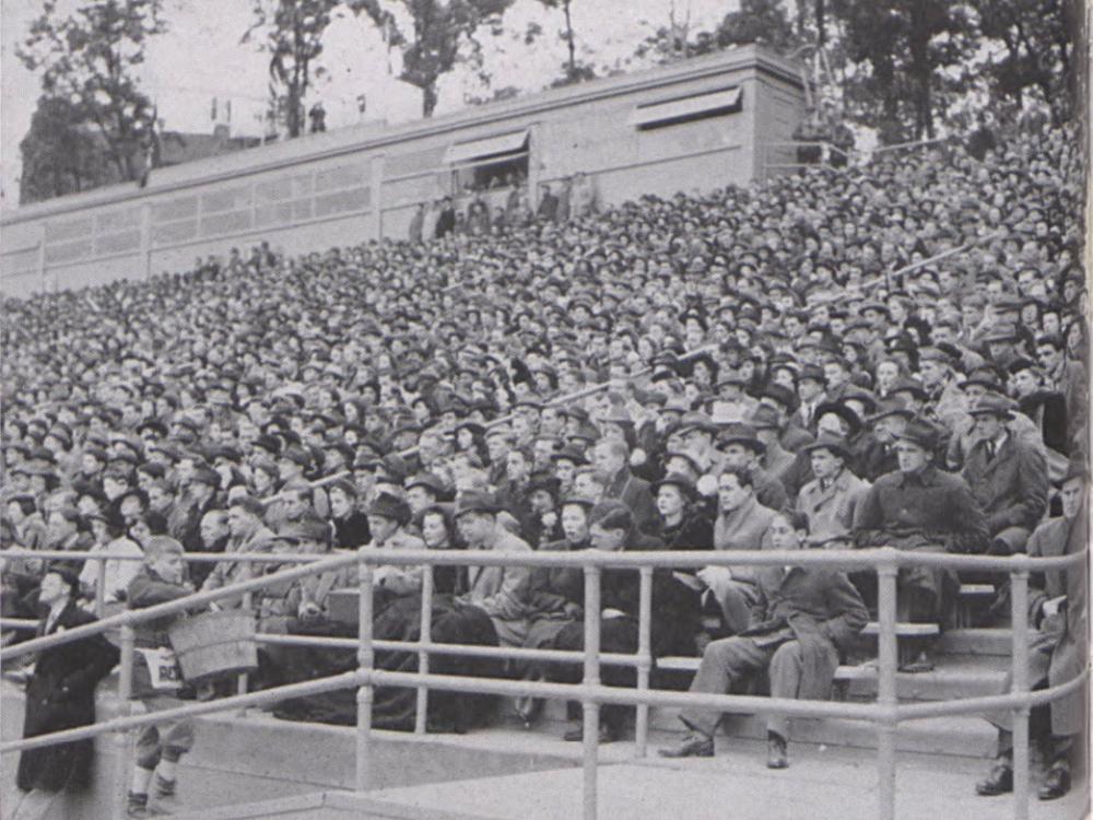 A black and white photo showing fans in the stands of a football stadium