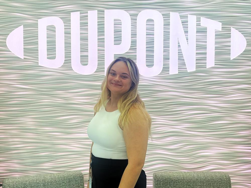 Paris Pavelchik in front of the DuPont logo at their office in Midland, Michigan