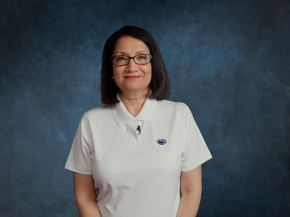 Neeli Bendapudi stands in front of blue studio background. 