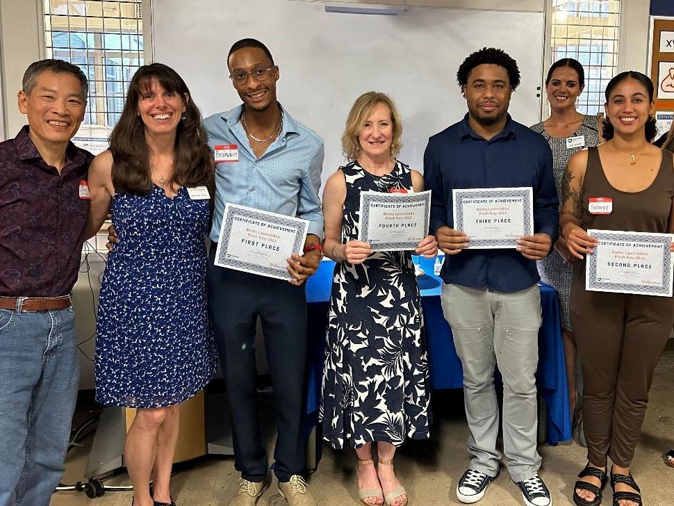 Seven people pose for a photo holding certificates