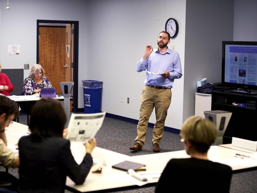 Man leading a workshop with attendees sitting in a U shape around him