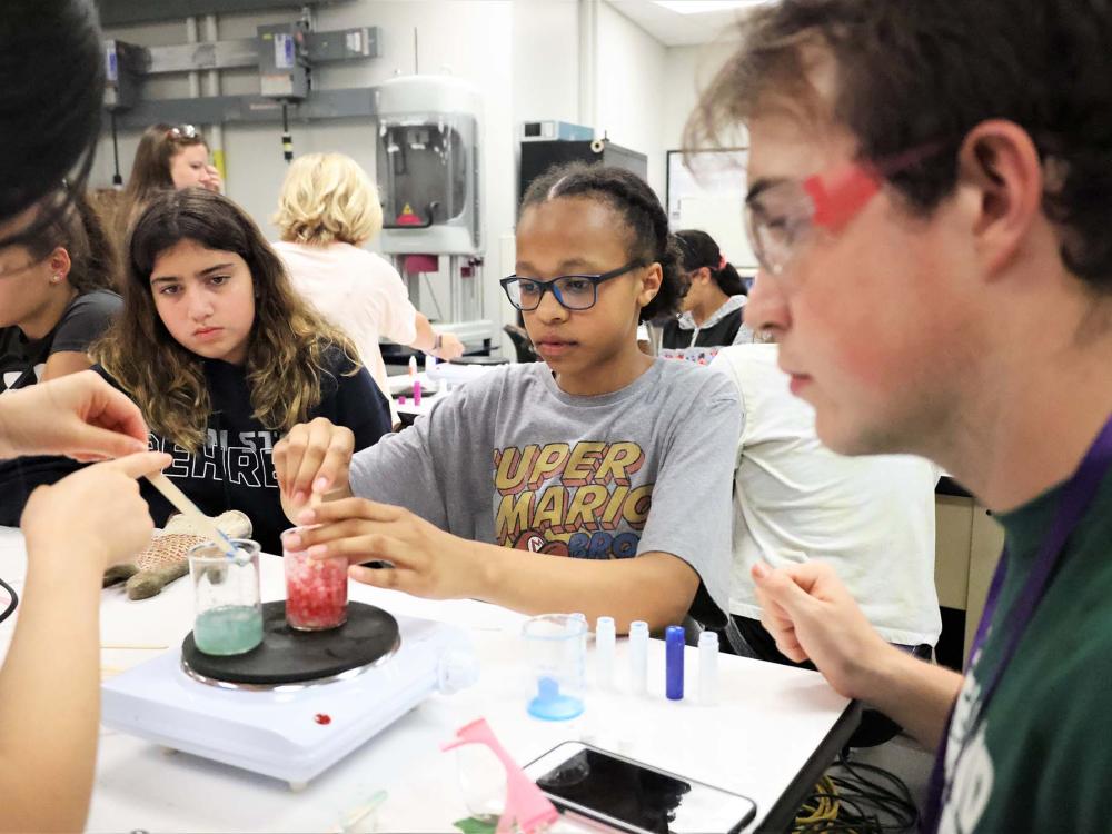 Several youth work with colored fluids in a lab at Penn State Behrend