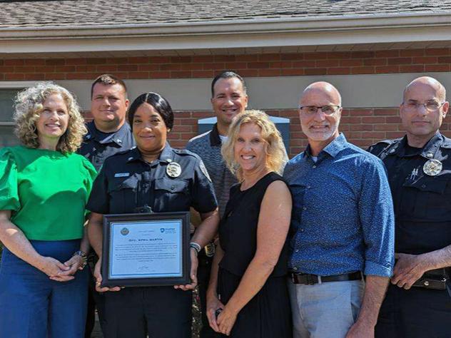 A photo of campus leadership and university officers with April Martin, in uniform, in the center holding an award plaque