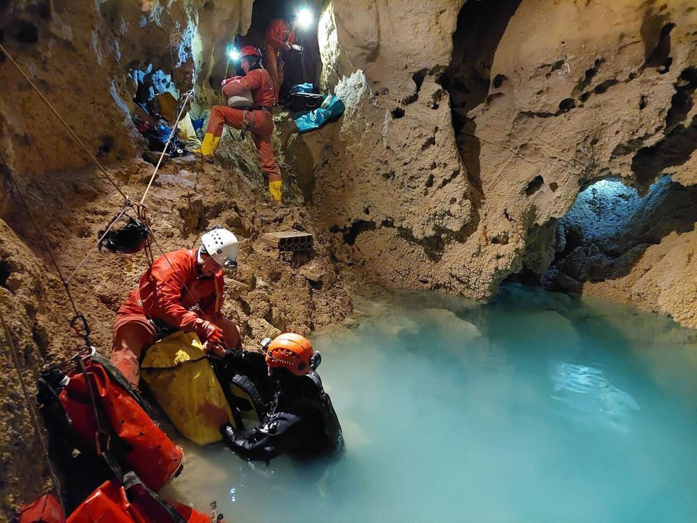 Researchers assist divers in obtaining samples from an underground lake