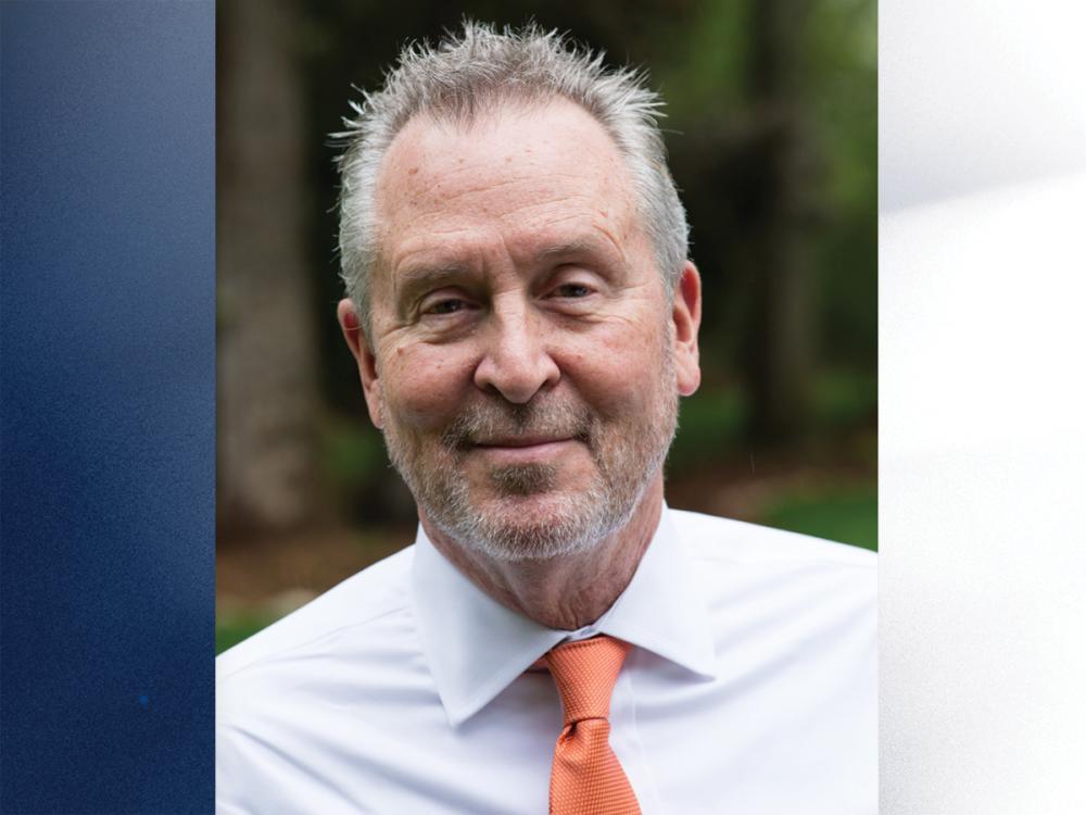 photo portrait of smiling man wearing white dress shirt and orange tie