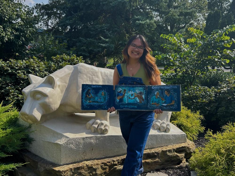 Person holding artwork in front of the Lion Shrine. 