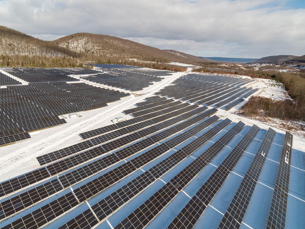 several solar panels arranged on the snowy ground, with mountains in the background