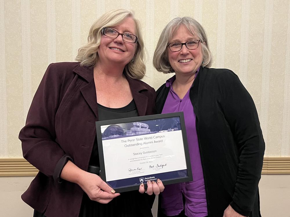 Stacey Gustavson, hold a framed award, stands next to her professor