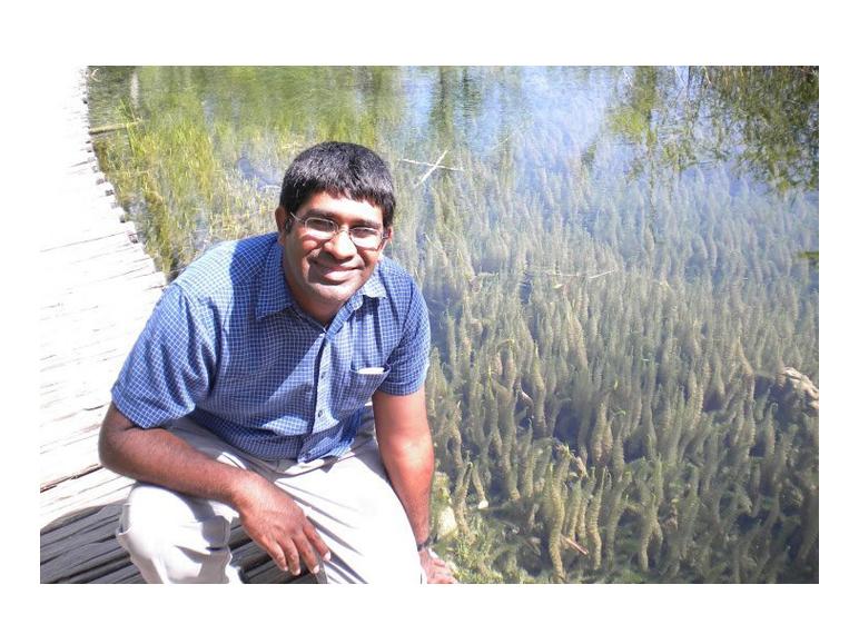 Suvrath Mahadevan kneeling on boardwalk near water