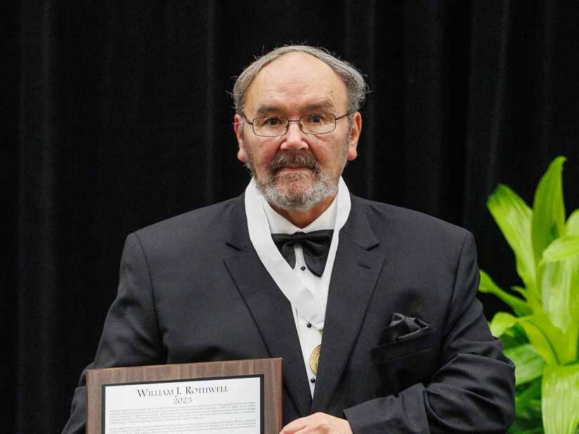 William Rothwell holds a plaque denoting his induction into the Hall of Fame.