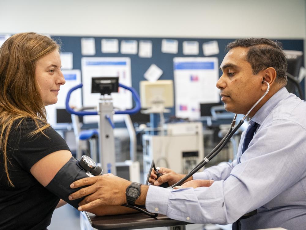 One person wearing a stethoscope takes the blood pressure of another person
