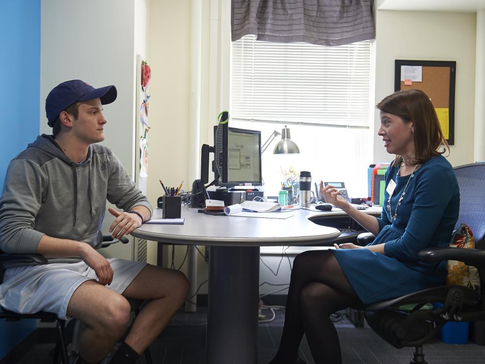 Students sitting across a desk talking with an academic adviser