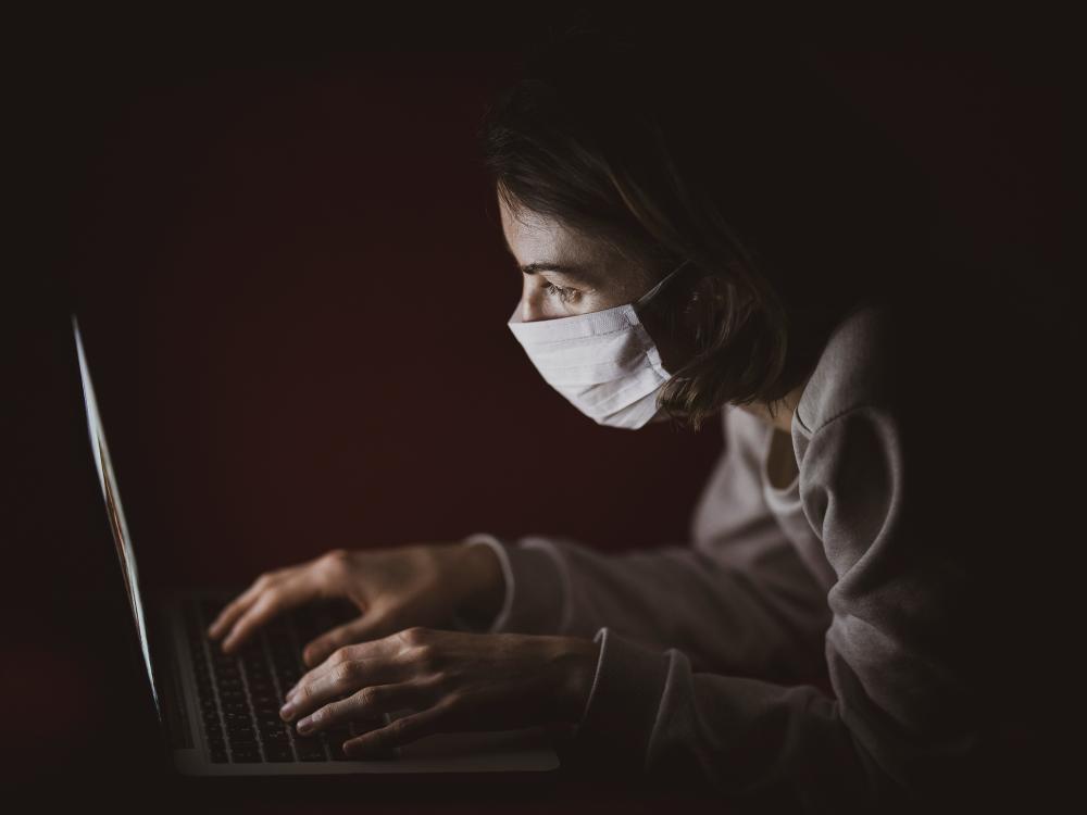 Woman in mask looking at computer