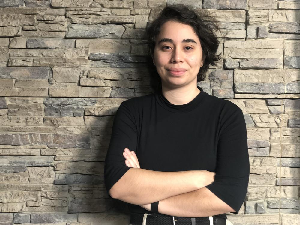 Dark haired woman in black shirt with arms crossed