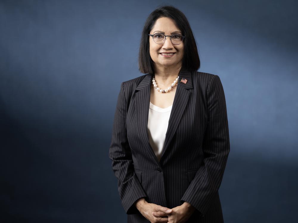 Neeli Bendapudi stands in front of a blue background in studio.