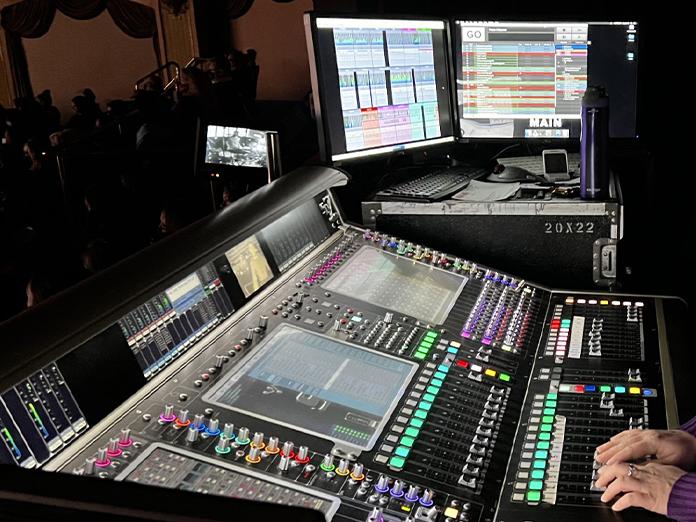 Theater production sound board with hands on knobs