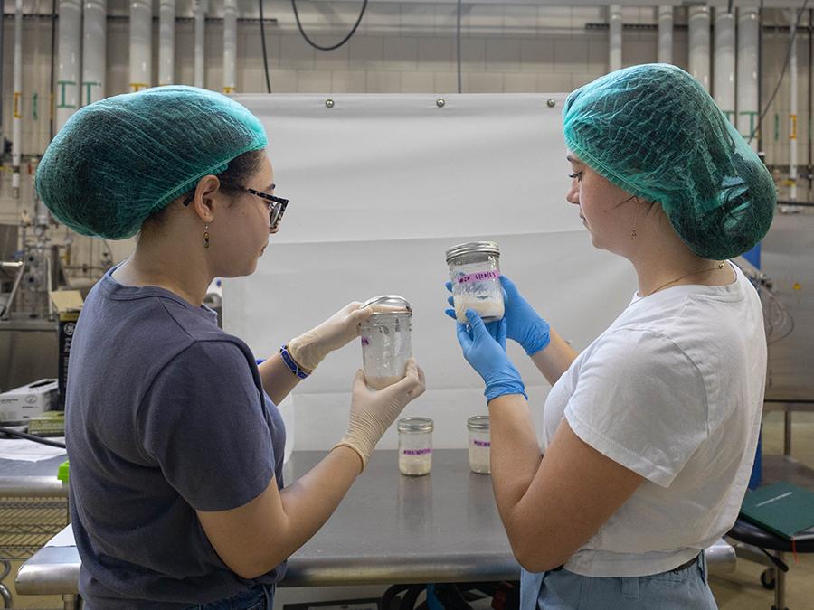 Two researchers with hair nets holding up sour dough starter