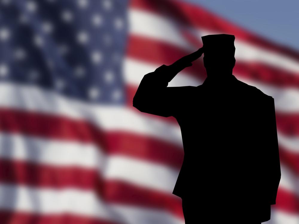 a silhouette of a solder saluting with the American flag in the background