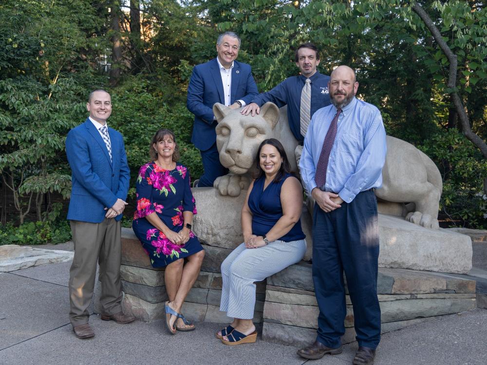 Six people posing with the lion shrine.