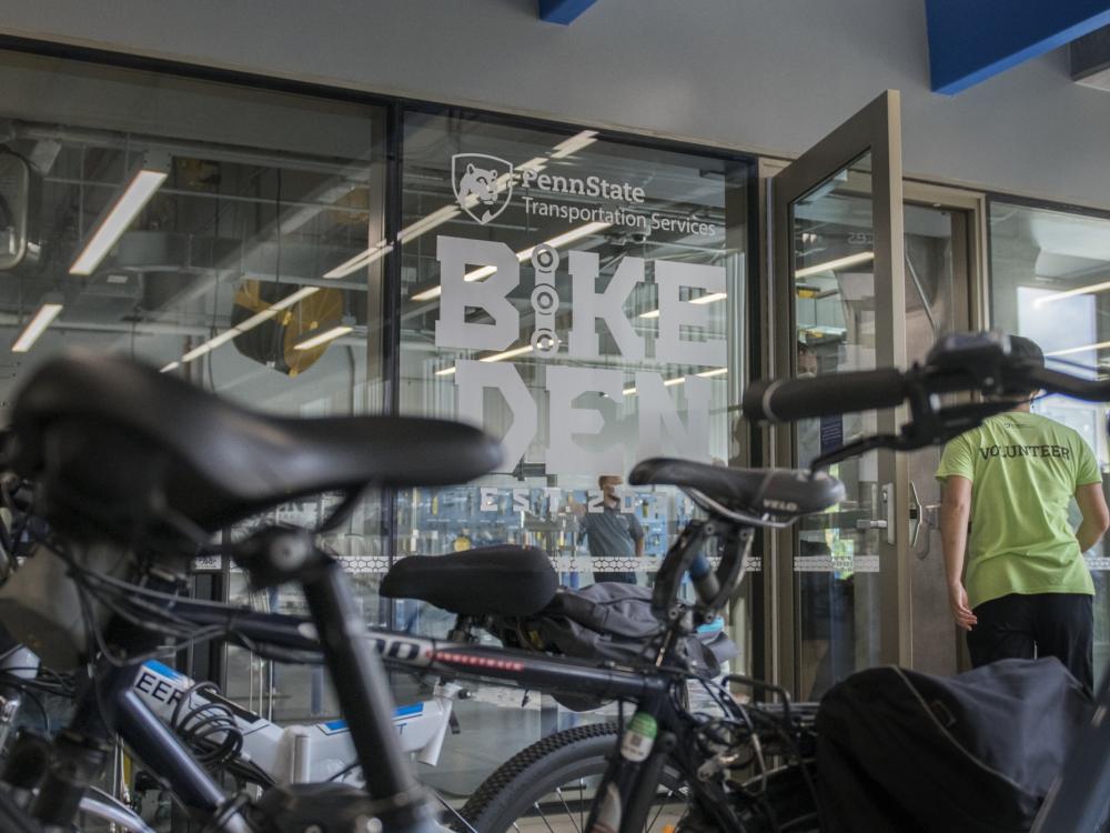 Rows of bikes outside the Bike Den. A person wearing a yellow shirt is walking in the door.