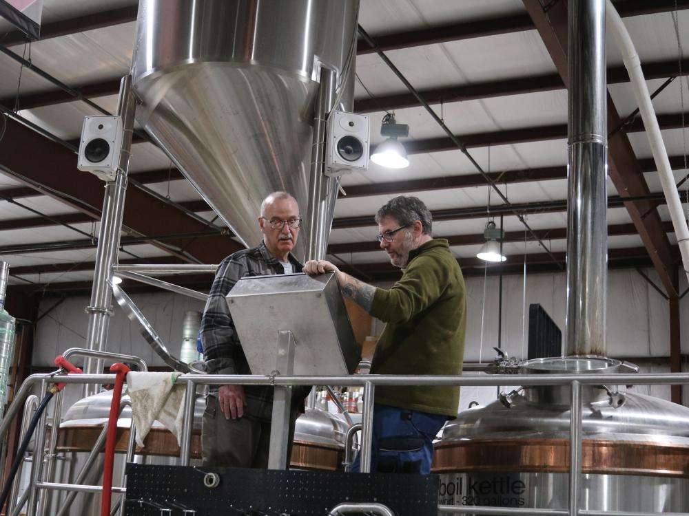 Two men in brewery looking thoughtful at screen