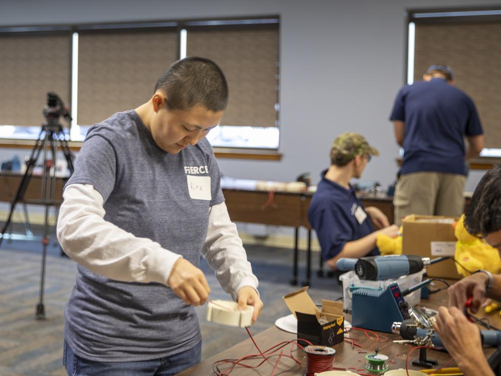 Berks student helps high school student with soldering toys.