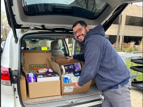 A man loads boxes of food and personal care items into a car