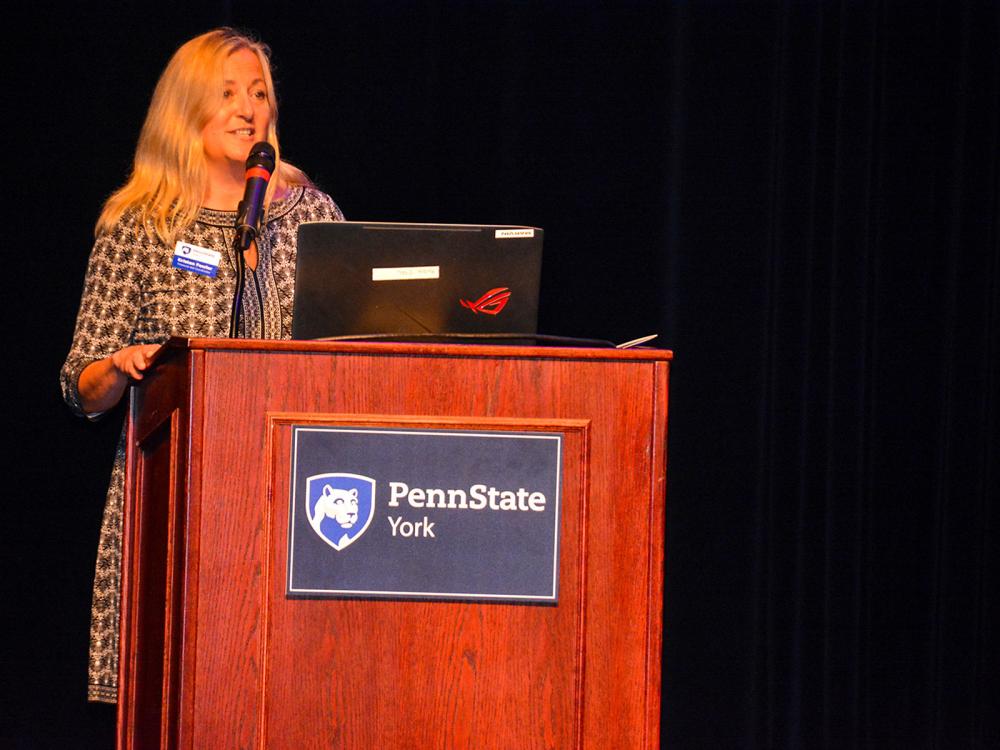 Woman with long blonde hair speaking at podium