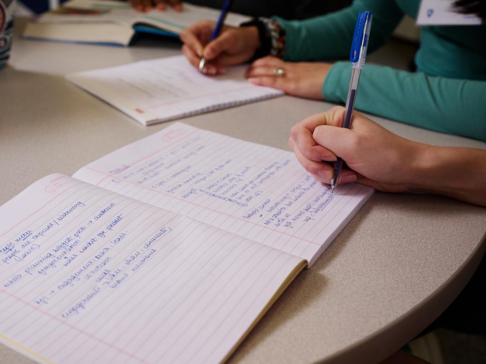 Person writing in notebook using a pen