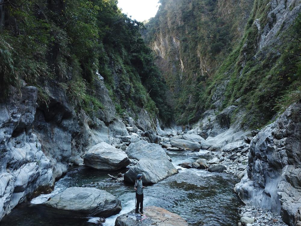 Roman DiBiase, associate professor of geosciences at Penn State, stands on a boulder in a river channel in central Taiwan